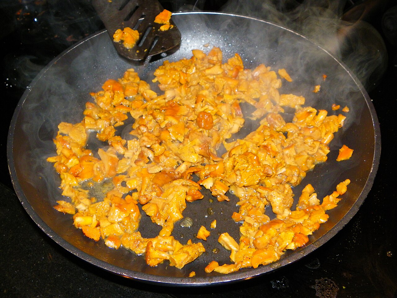 Golden chanterelle mushrooms sizzling in a frying pan