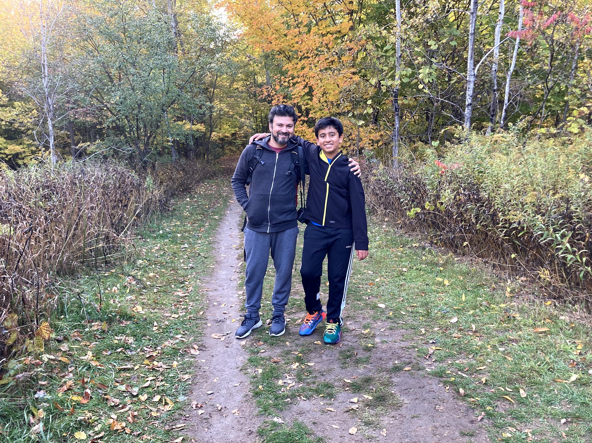 Varun and his son on an autumn forest trail in Ontario